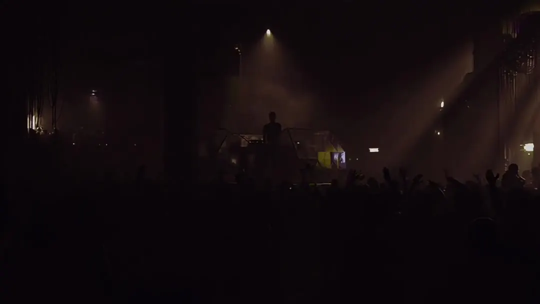 Een donkere rave: een menigte in silhouet, gericht naar één lichtbron op een podium